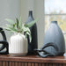 Decorative vases and a plant on a wooden surface with a blurred background